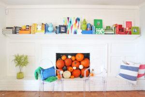 fall mantel decoration with pumpkins - Pencil Shavings Studio - Colorful - Painted white brick mantel - lucite chairs - www.pencilshavingsstudio.com