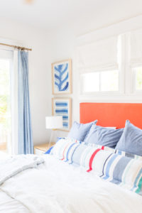 Lake house master bedroom suite reveal - bright white and chambray blue - upholstered headboard - stripe lumbar pillow - cane accent chair - cb2 - lake house decor - lake house bedroom - coastal style - coastal bedroom www.pencilshavingsstudio.com